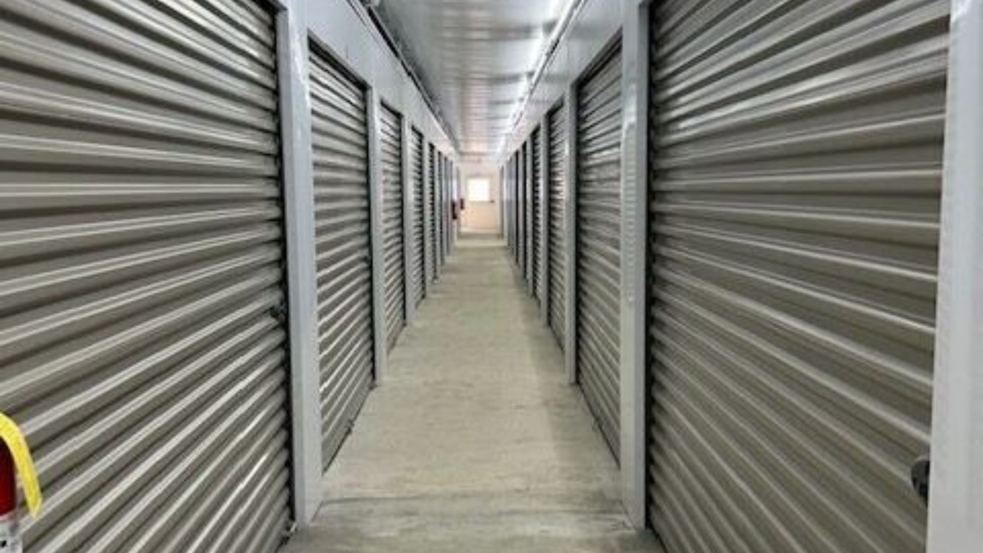 Indoor storage unit corridor with rows of grey metal roll-up doors