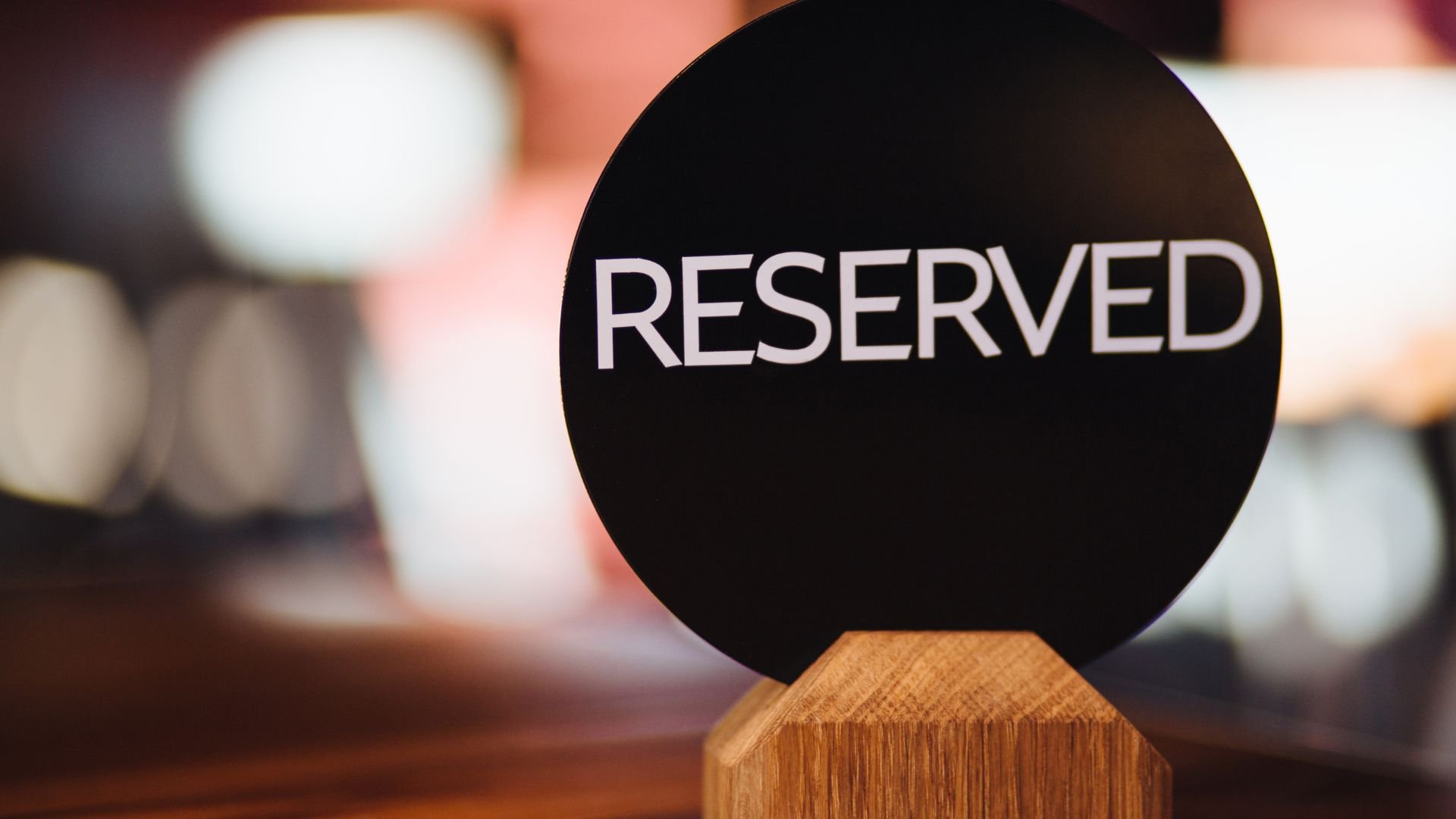 Black round reserved sign on wooden stand with blurred background