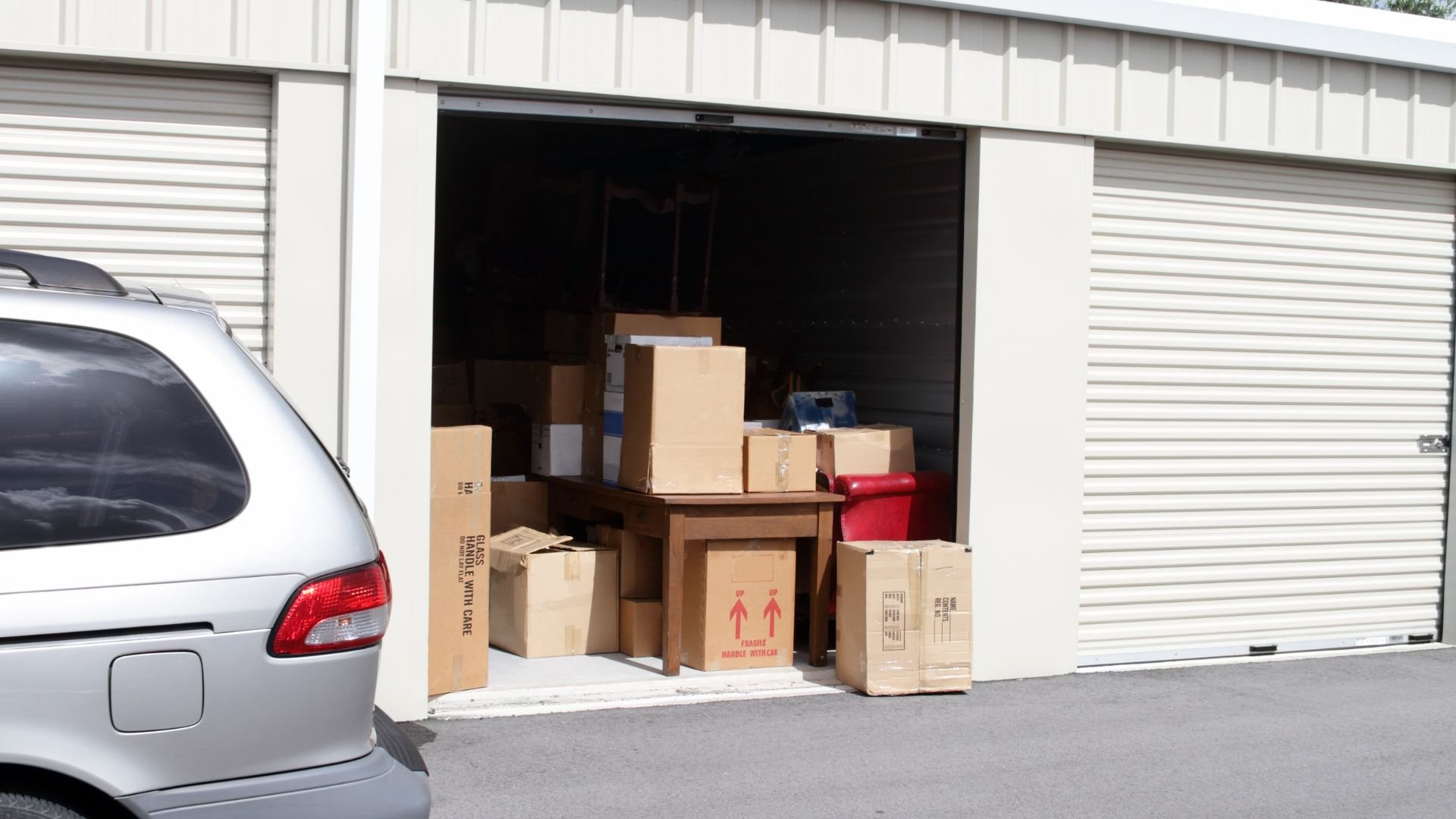 Storage unit with cardboard boxes and a partial view of a vehicle