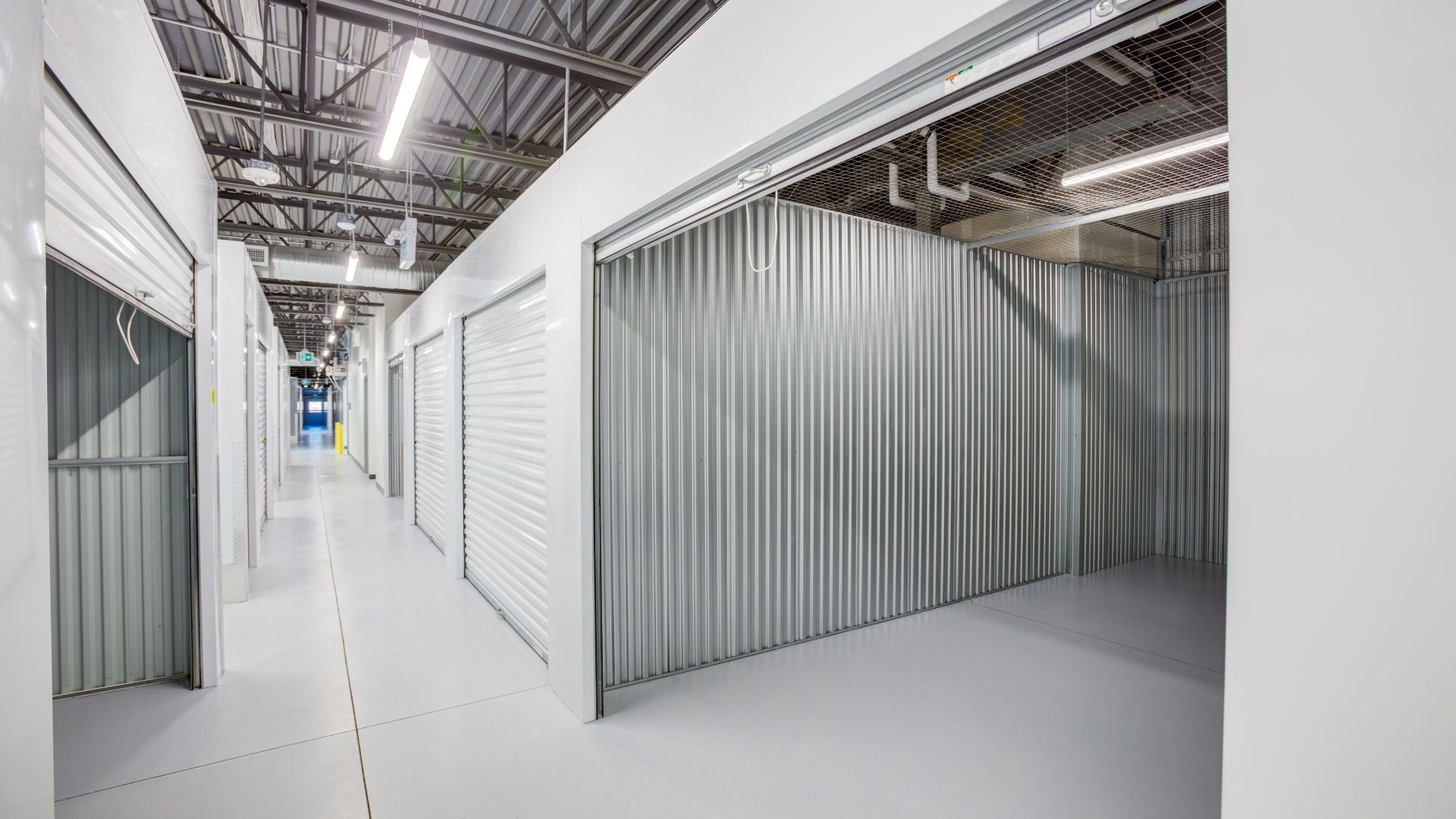 Interior of a clean, modern self-storage facility with white and metal units