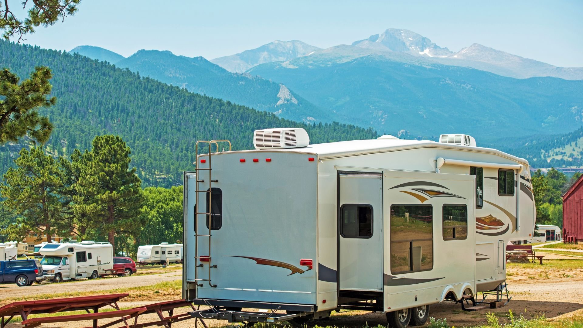 White RV parked at campground with mountain landscape in background
